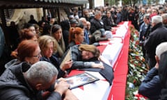 A large crowd of mourners gather around coffins draped in the flag of northern Cyprus