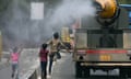 Children run behind a truck spraying water along a street in New Delhi, as the city records a record temperature of 49.9C.