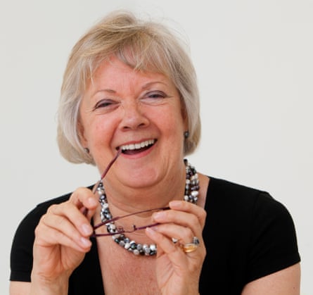 Dame Mary Perkins smiles holding a pair of specs