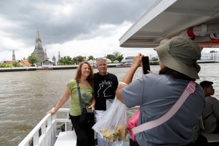 Foreign tourists pose for a photograph with the Wat Arun temple in the background.