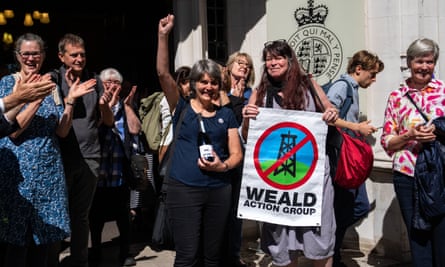 Finch holds bottle of bubbly with label reading ‘we won’ as she is flanked by fellow campaigners outside court
