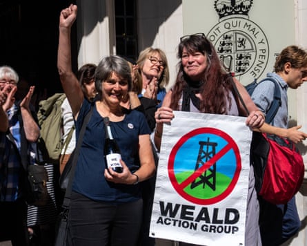 Sarah Finch raises a fist in the air outside the supreme court in London next to another woman holding a Weald Action Group sign