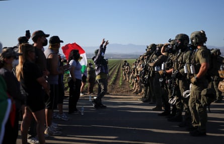a group of people stand in front of armed agents