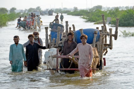People wade along a flooded road in the Jaffarabad area of Balochistan province.