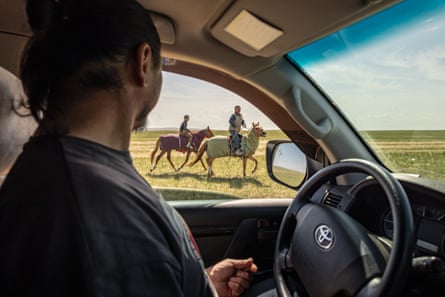 Ranger M Batbaatar sitting in the driver's seat of a truck talks through the window to two people sitting on horses