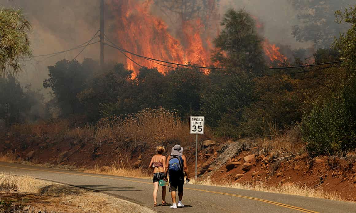 Fire near road where two people are crossing