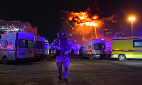 Person in uniform walks forward as flames blaze in the back