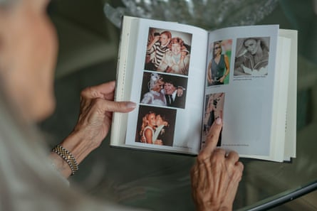Close-up of a woman’s hands, holding a hardback book with family photographs