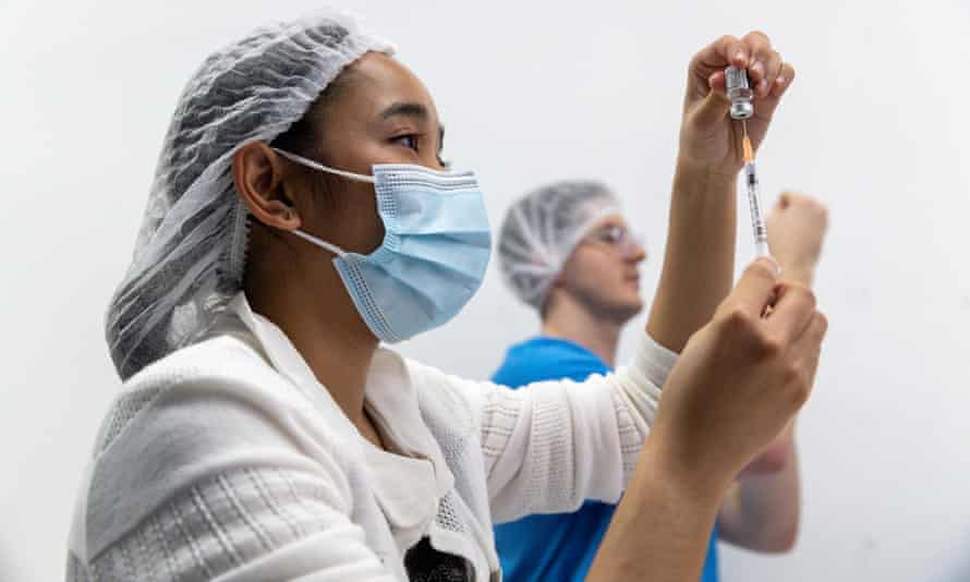 Health care workers fill syringes with the Pfizer vaccine at a mass vaccination clinic in Midland, Perth.