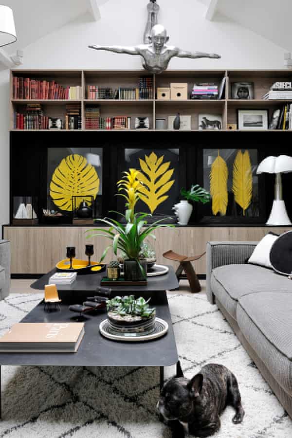 Hoch hinaus: Gepresste Farne zieren das in Weiß und Hellgrau gehaltene Bücherregal im Wohnzimmer. Es ist ein beliebter Schlafplatz für die französische Bulldogge der Familie.