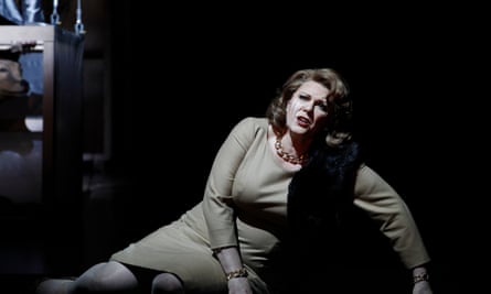 A woman sits on the floor of a stage and sings