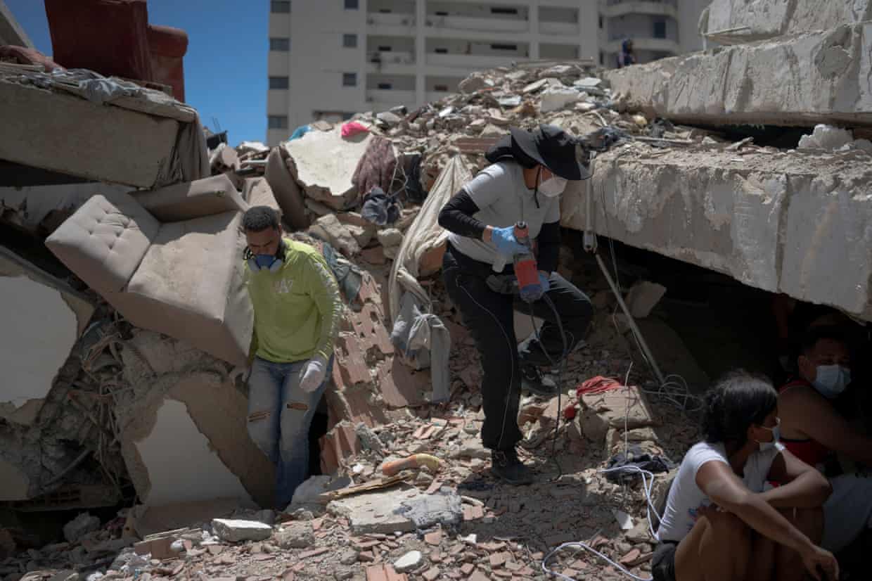 Woman amid wreckage wearing a dust mask and holding an electric drill