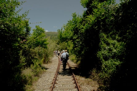 People walk along a railway track, seen from behind