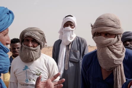 Members of BAF stand listening to a debrief from leader Ahmedou Ould Boukhary after the training session while dressed in long tunics and tagelmusts head scarves.