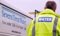 a man in a hi-viz jacket labelled WATER passes a Severn Trent Water sign on a van