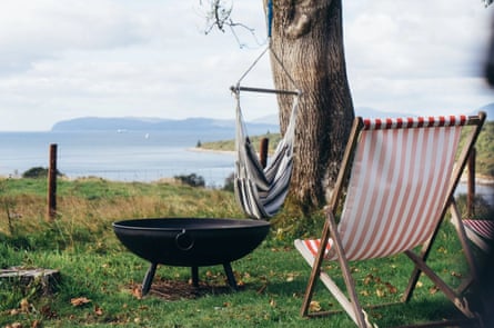 A deckchair, hammock seat and firepit all looking out over the water