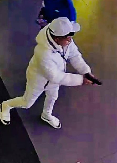 A young man in a white outfit and hat holding a pistol.