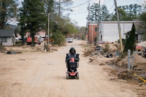A man in a mobility scooter on a street strewn with debris