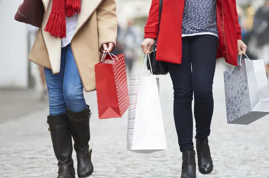 Friends carry Christmas shopping on a busy street.