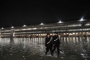 Police patrol across the flooded St. Mark’s square