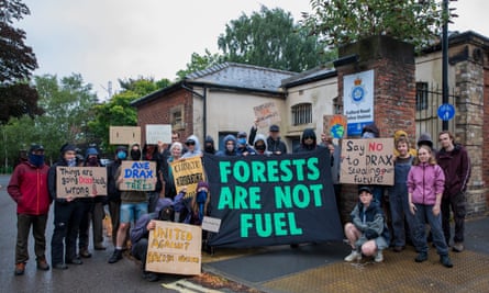 Protesters outside Fulford police station: their placards and banners have messages including Forests are not Fuel, Axe Drax not Trees, Things are Going Draxtically Wrong, Stop Burning Trees and Subsidise Real Renewables