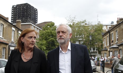 Jeremy Corbyn walks down a street in north Kensington with Grenfell Tower in the background