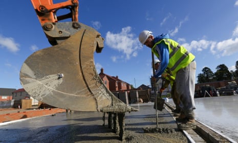 A photo of a builder levelling off mortar on the floor of a new residential home during construction at a Bellway site in Northampton, UK.