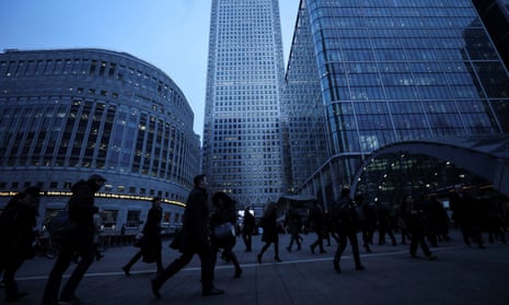 Workers walk to work during the morning rush hour in the financial district of Canary Wharf in London