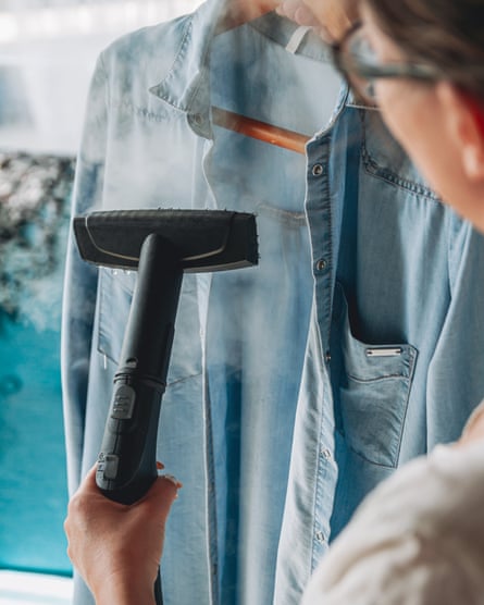Woman is steaming a steam cleaner shirt in a room at home