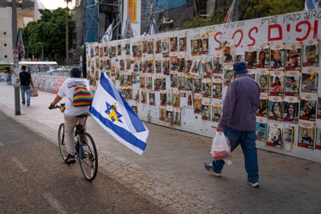 Passersby observe the photos of hostages, held in the Gaza Strip, that are on the walls of a plaza known as Hostages Square in Tel Aviv.