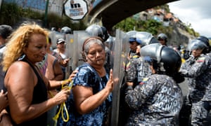 People confront riot police during a protest in Caracas against the shortage of food.