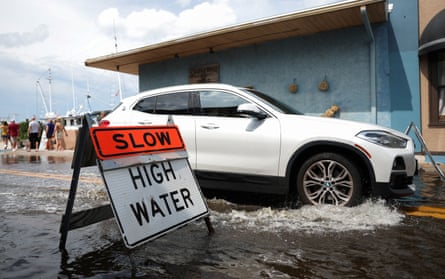 A vehicle drives through a flooded street as Hurricane Isaias causes 1–3 ft. of additional high-tide flooding
