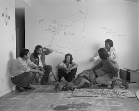 A group of people sitting in a room with maps on the wall.