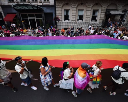 A large rainbow flag being carried through the streets of London