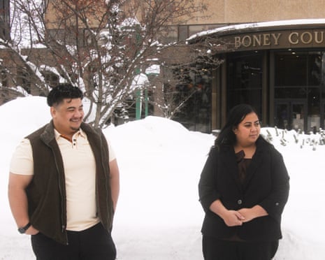 man and woman stand outside courthouse, snow on the ground behind them