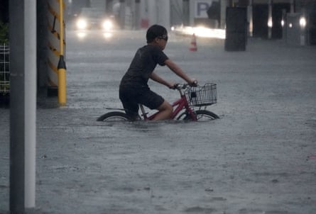 A boy cycles through a flooded street