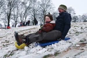 A father and son ride a sledge at Swan Pool Park, Stourbridge, England