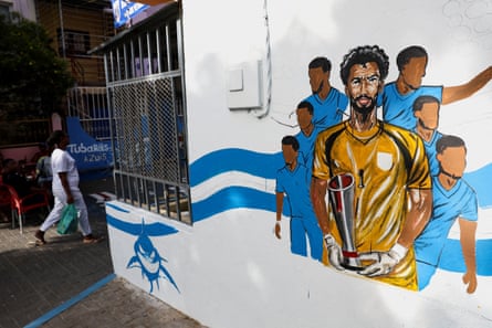 A personification walks past an image depicting Vozinha connected a thoroughfare successful Praia.