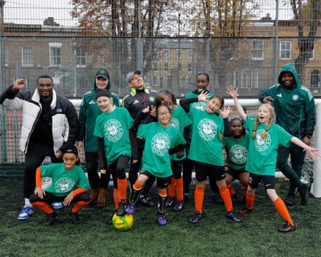 Young girls from Dulwich Village football club pose for a team photo with coaches during a tournament hosted by the Celtic FC Foundation at the Ferndale Sports Centre in Brixton