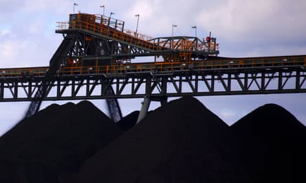 three piles of black coal and horizontal yellow metal structures above