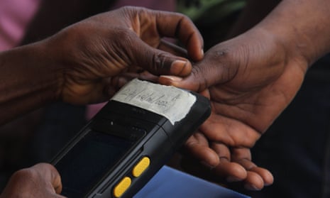 An electoral officer scans the thumb of a voter using a biometric system at a polling station in Lagos.