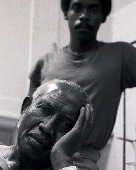 Charles Burnett rests his head on his hand, with a younger man standing behind him