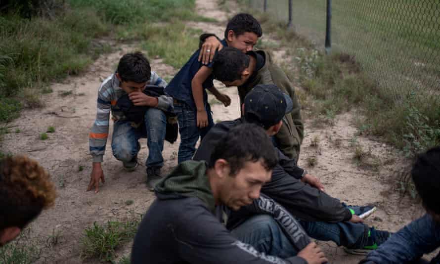 A four-year-old boy weeps in the arms of his uncle as he and others were apprehended by border control agents near the US border.