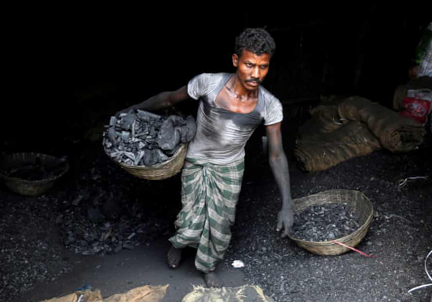 Un trabajador lleva carbón en una canasta en una zona industrial de Mumbai.