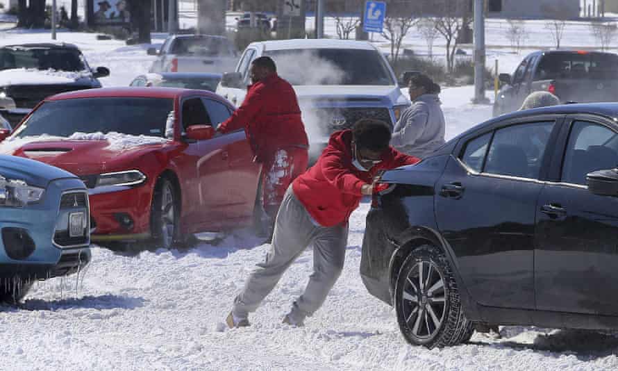People push a car free after spinning out in the snow in Waco, Texas.
