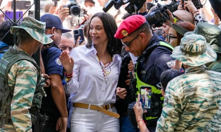 María Corina Machado rodeada de personas con cámaras y hombres con equipo de camuflaje