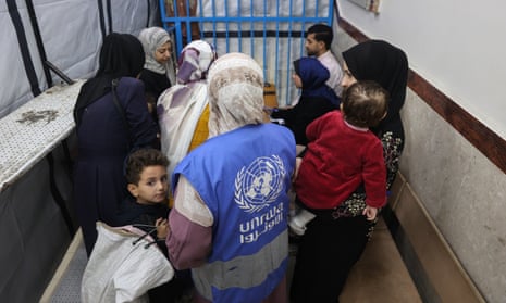 A staff member helps Palestinian families awaiting care at an Unrwa-run clinic at al-Shati refugee camp west of Gaza City this week