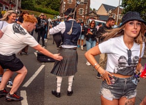A fan touches the kilt of a man playing the bagpipes.