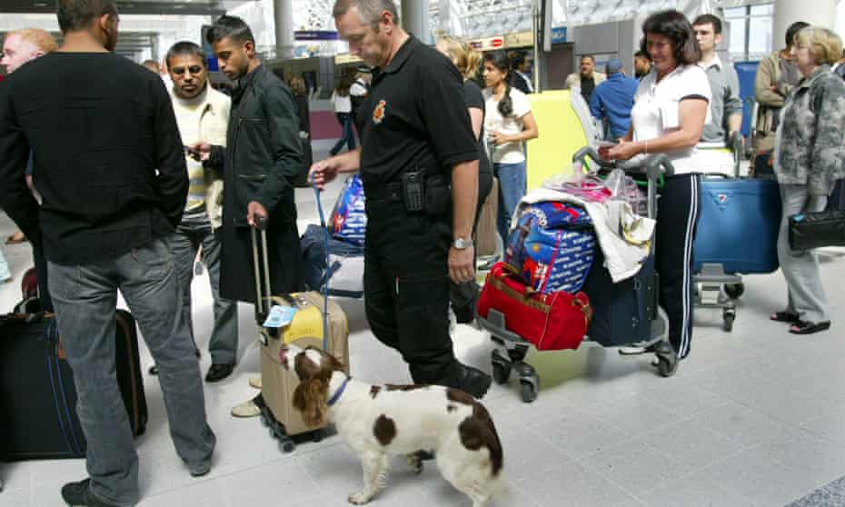 A sniffer dog and its handler check departing passengers at Manchester airport