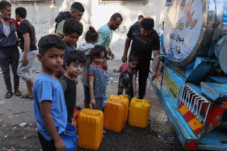 Palestinians fill jerrycans at a public water collection point, 12 October.